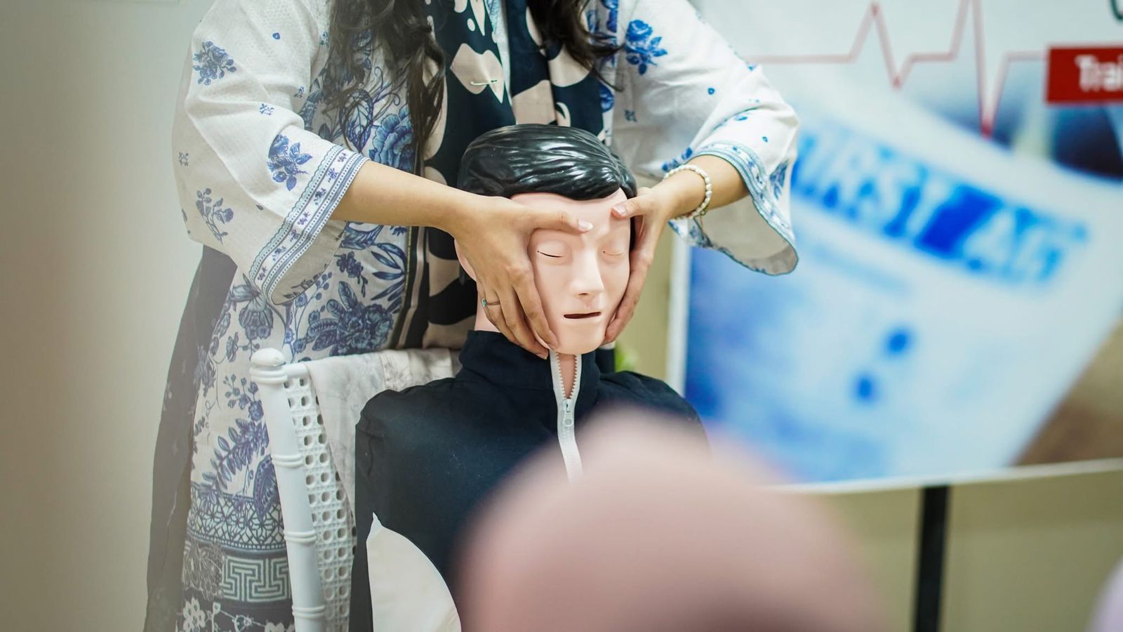 Instructor positioning a manikin's airway during a BLS workshop